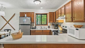 A modern kitchen with wooden cabinets, stainless steel appliances, and a large island. - 7mins to Skiing, Fire Pit, Game Table Lake Access Hygge Home by Avantstay (Blakeslee)