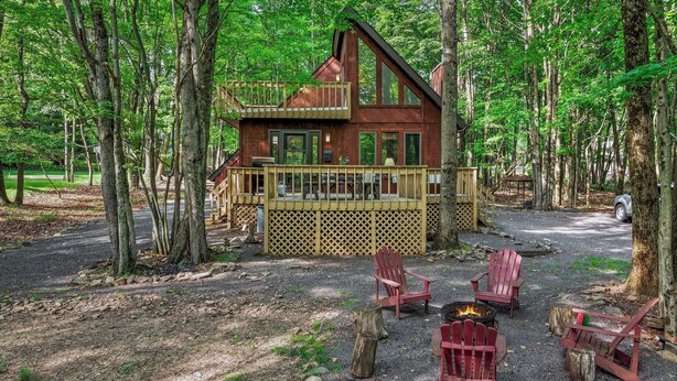 A cabin with a deck, surrounded by trees, and a fire pit with chairs. - 7mins to Skiing, Fire Pit, Game Table Lake Access Hygge Home by Avantstay (Blakeslee)