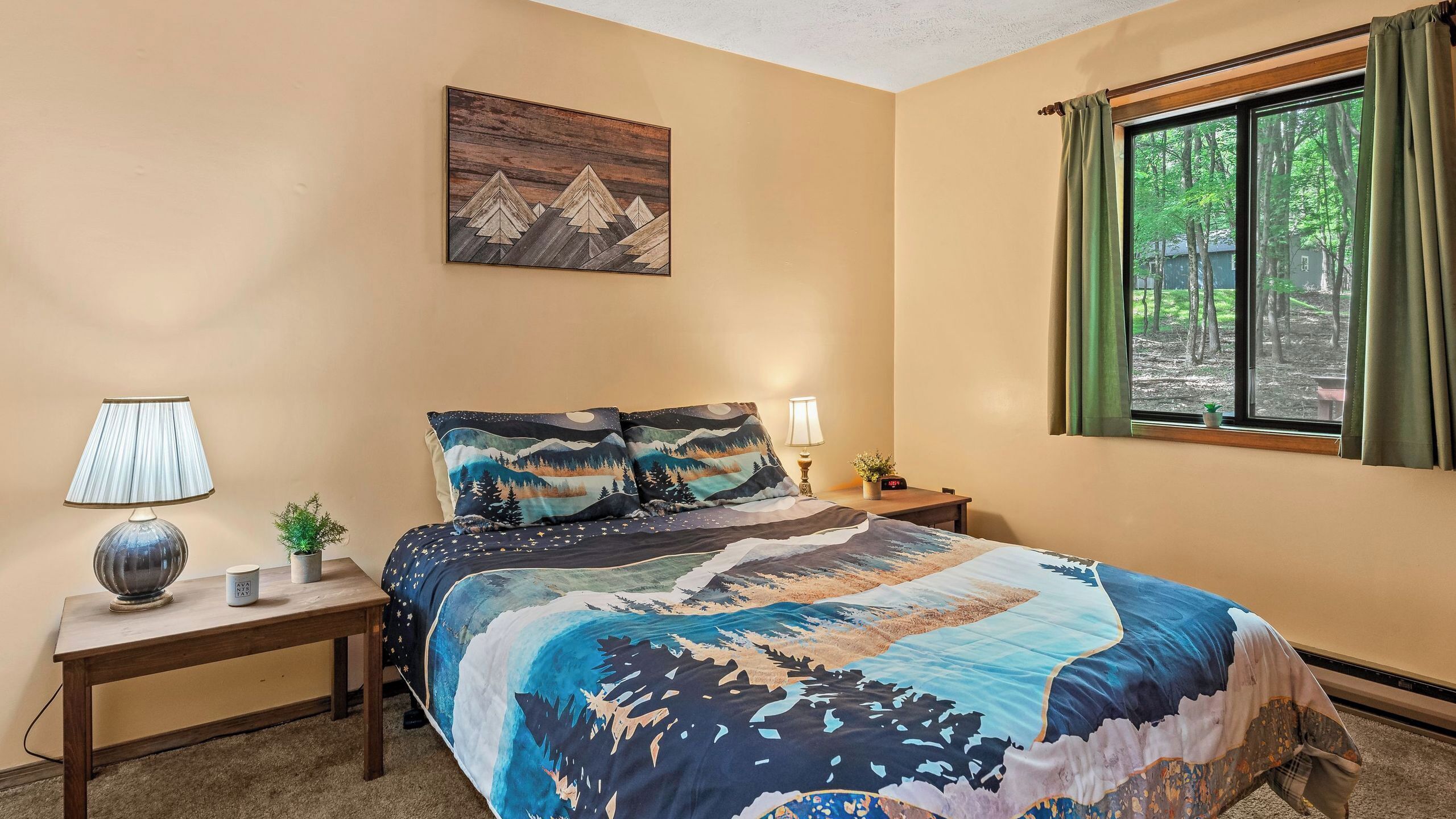A bedroom with a bed, two bedside tables, a nightstand, a window with curtains, and a wall-mounted painting.