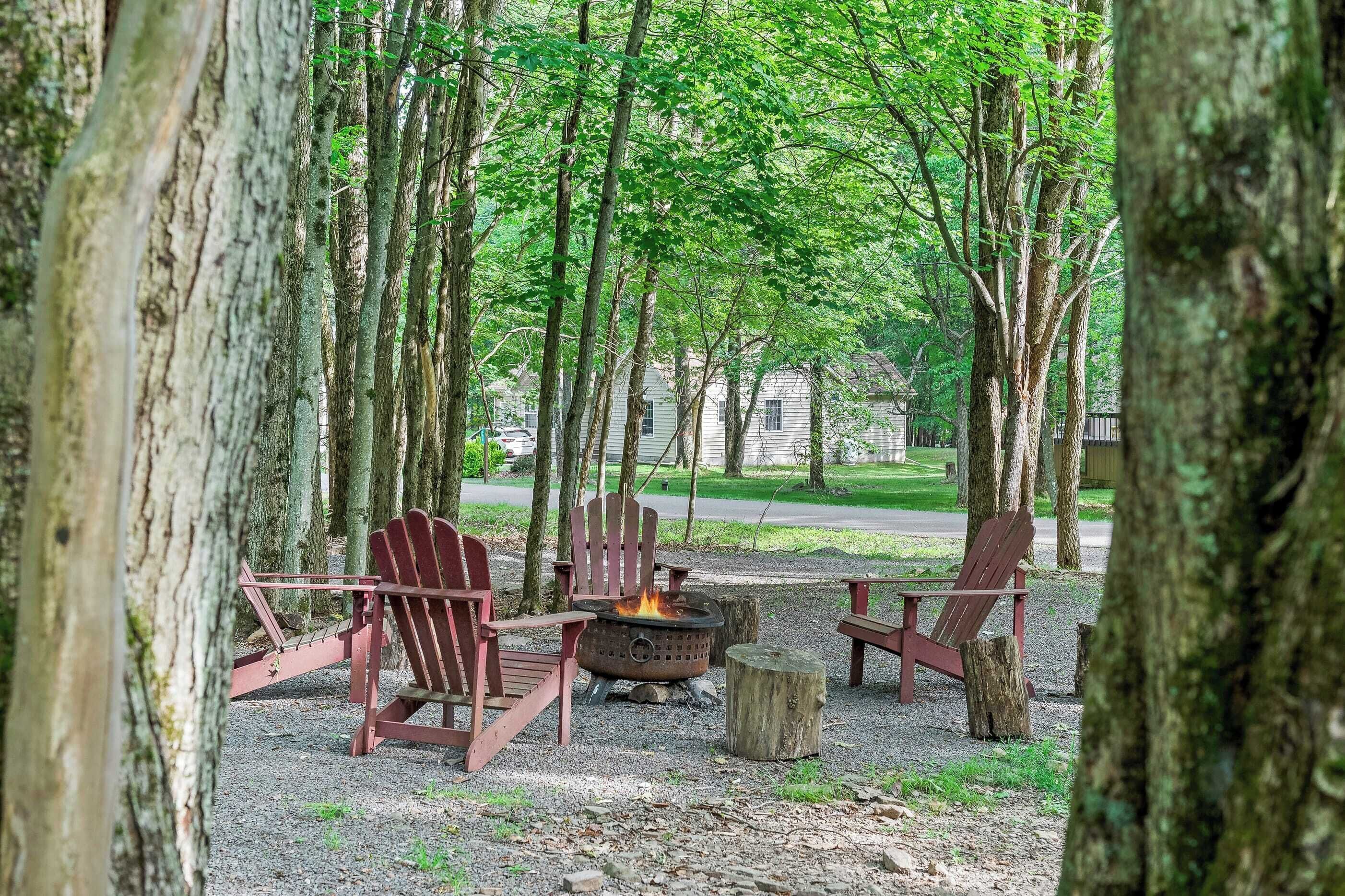 A campsite with a fire pit and Adirondack chairs.