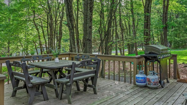 A wooden deck with a table and chairs, surrounded by trees.