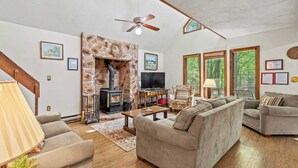 A cozy living room with a stone fireplace, a television, and comfortable seating. - 7mins to Skiing, Fire Pit, Game Table Lake Access Hygge Home by Avantstay (Blakeslee)