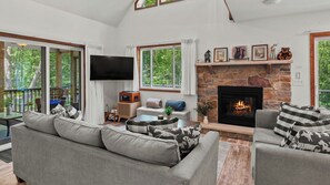 Ein Wohnzimmer mit Kamin, Fernseher und einer Couch mit gemusterten Kissen.