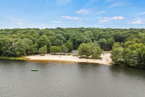 Une vue sur le lac, avec une plage de sable, des arbres et un petit bateau.
