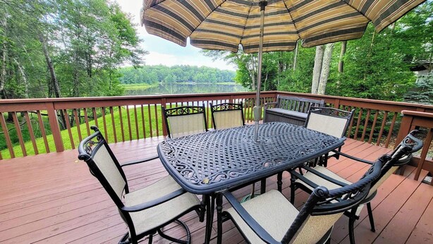 Eine Terrasse mit Tisch und Stühlen, umgeben von einer Holzbrüstung, mit Blick auf eine natürliche Landschaft.
