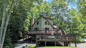 A cabin with a deck and a staircase leading to a second floor.