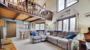 Ein geräumiges Wohnzimmer mit einer großen Eckcouch, einer Holztreppe und einem Essbereich.