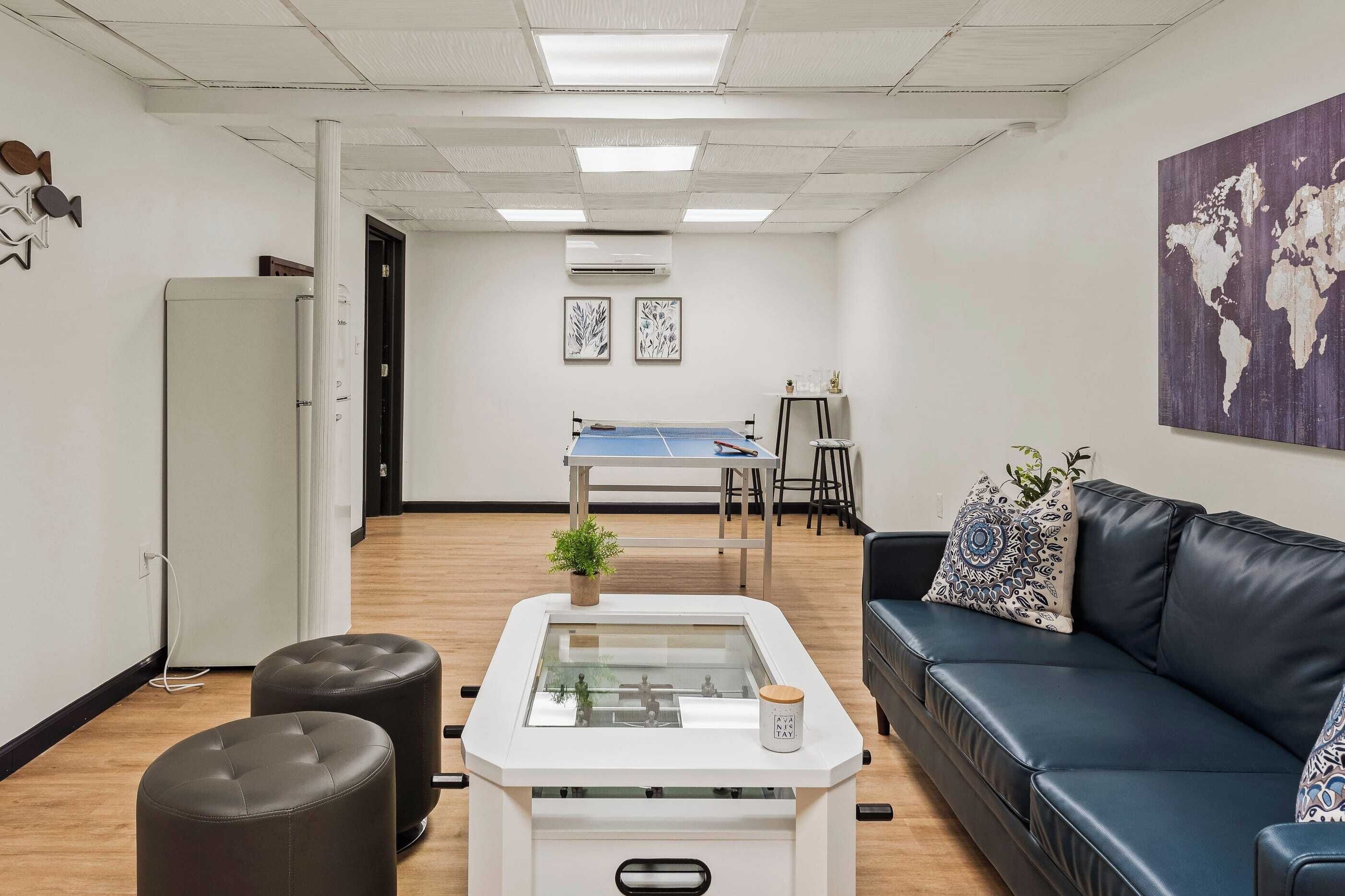 A modern office space with a ping pong table, a sofa, and a small coffee table.