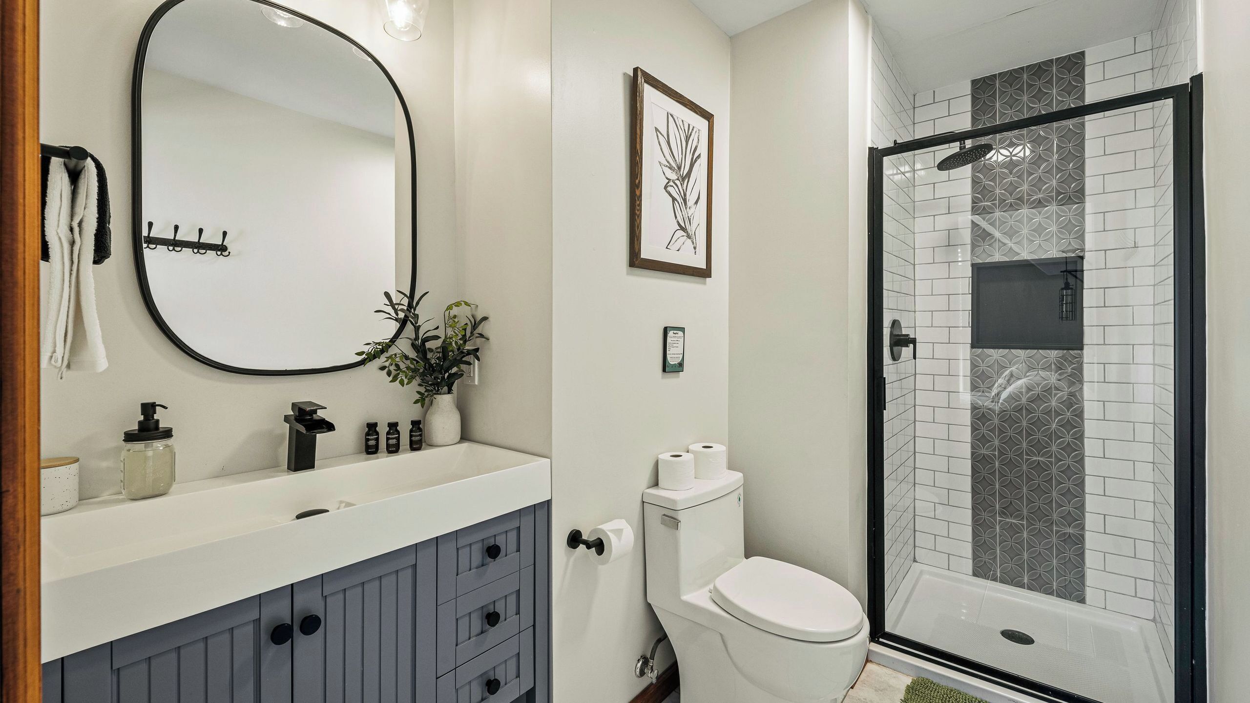 A bathroom with a white sink, a mirror, a toilet, and a shower area.