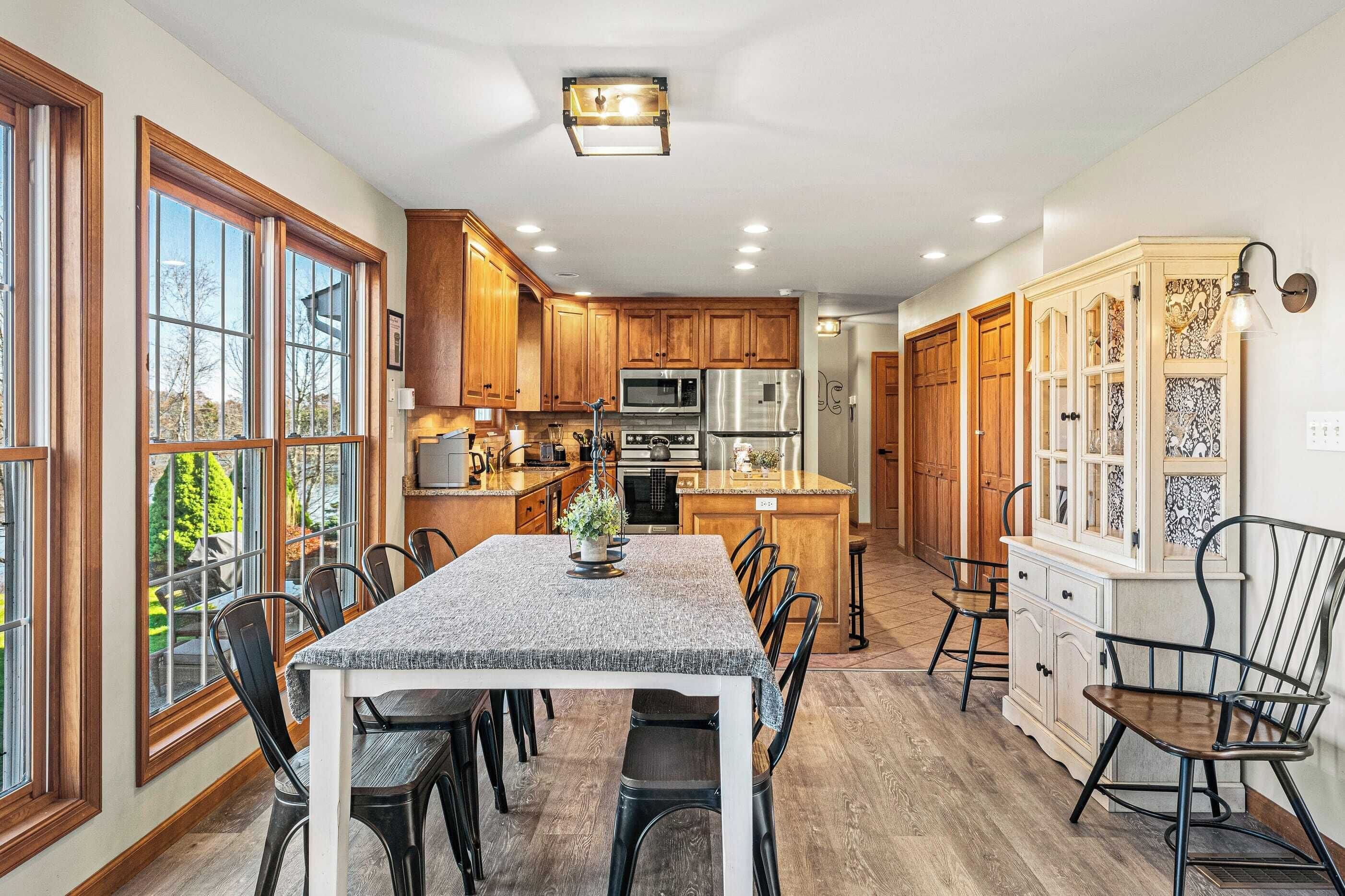 A spacious kitchen with wooden cabinets, a central island, and a dining area with chairs.