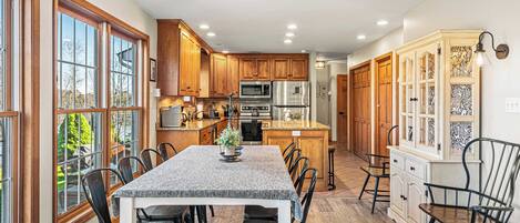 A spacious kitchen with wooden cabinets, a central island, and a dining area with chairs.