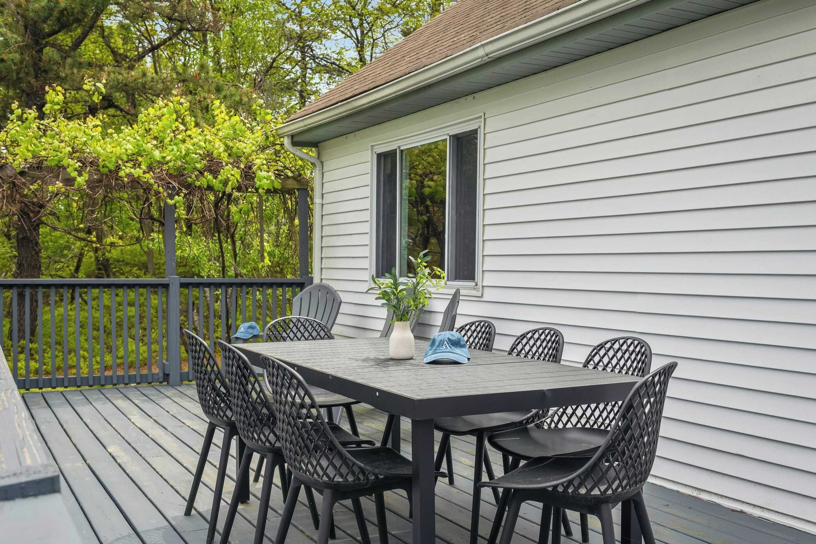 Une terrasse avec une table et des chaises, un pot de fleurs et une vue sur les arbres.