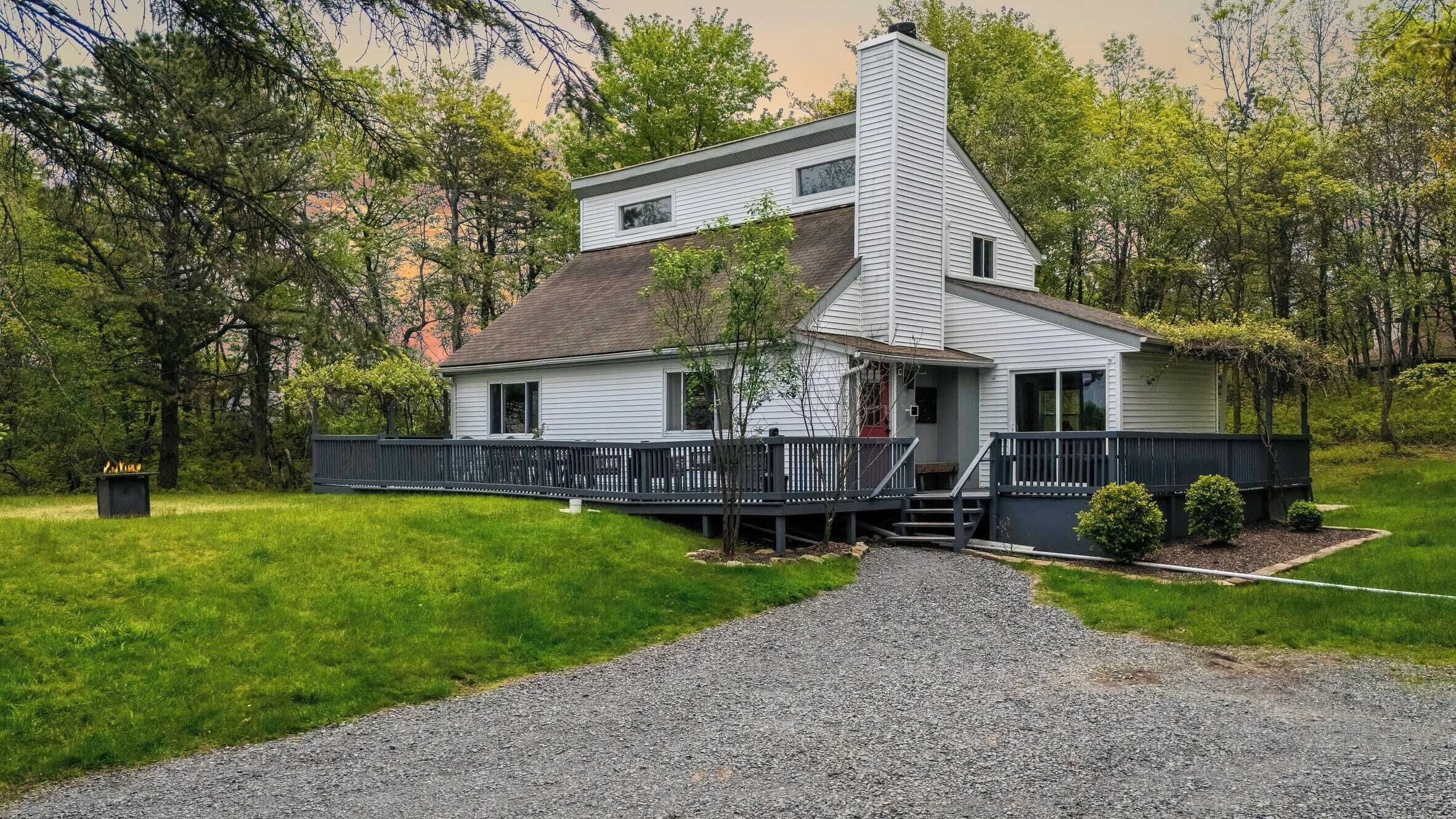 A two-story house with a covered porch and a chimney.