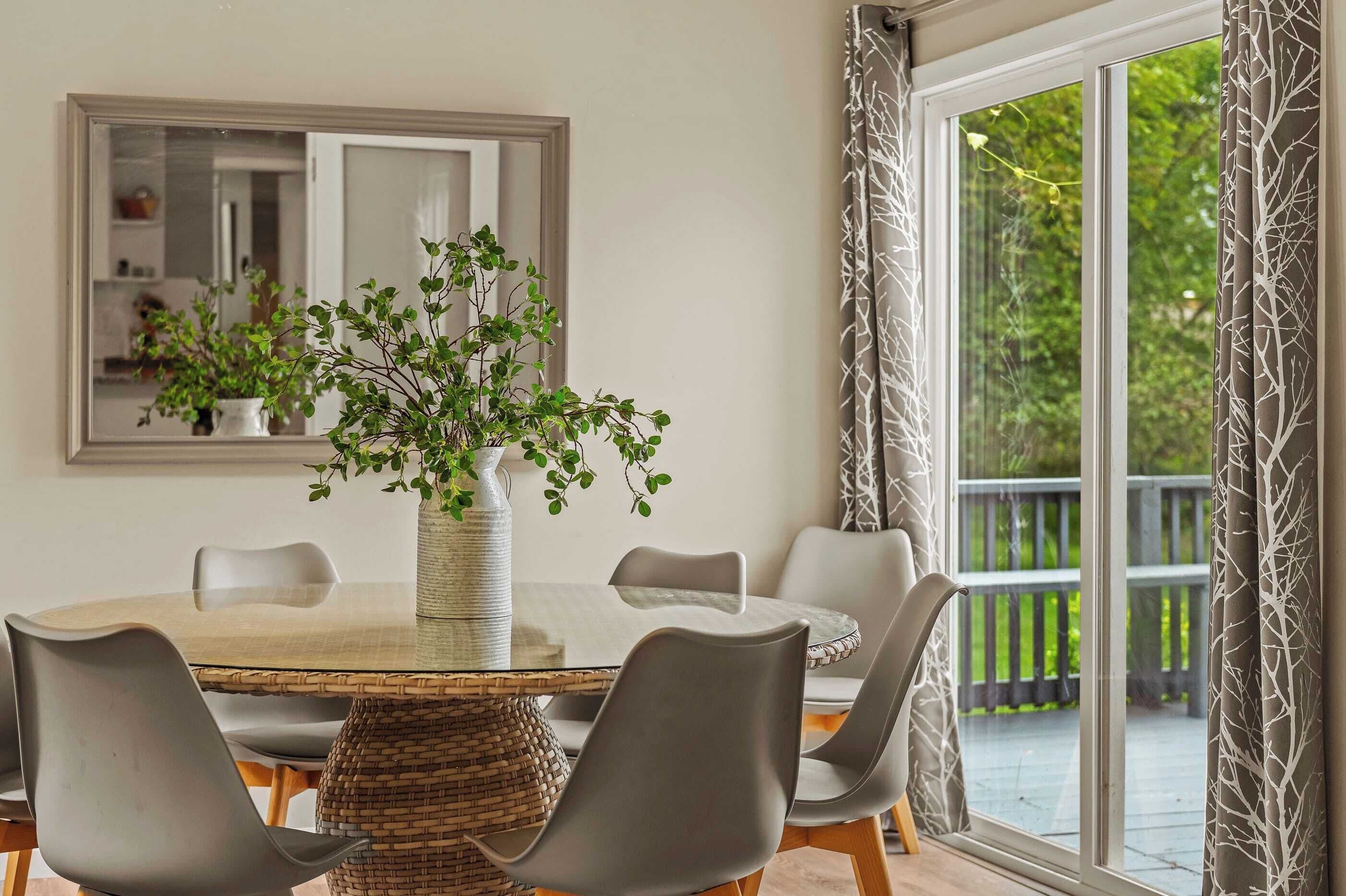 A dining area with a round table, grey chairs, a woven basket, and a potted plant.