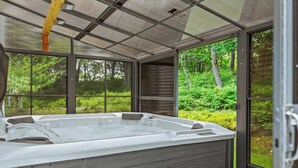 Un bain à remous avec vue sur un jardin luxuriant et des arbres.