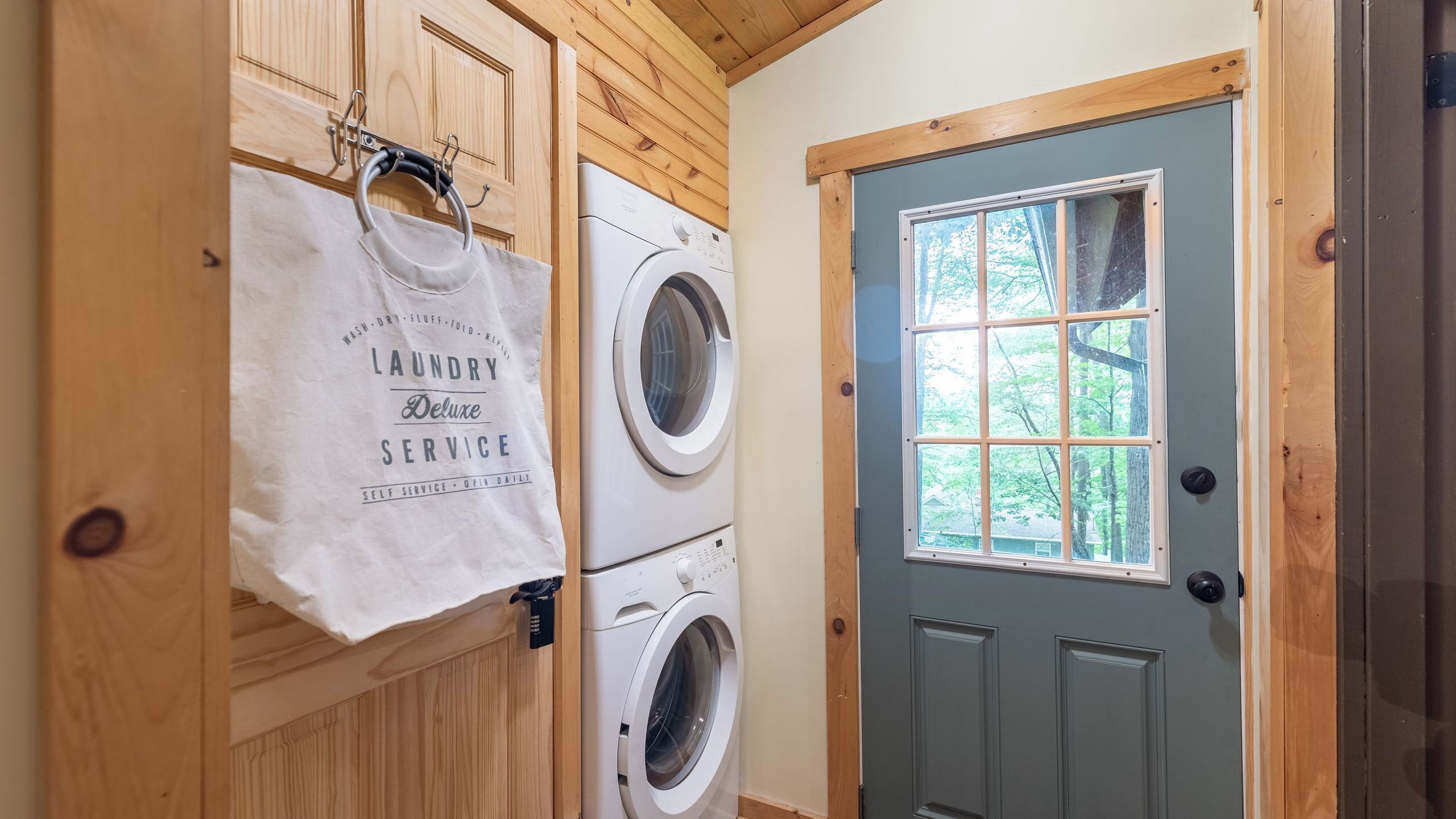 Une buanderie équipée d’un lave-linge, d’un étendoir et d’une porte avec une fenêtre.