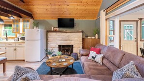 A cozy living room with a stone fireplace, wooden ceiling, and a comfortable couch.