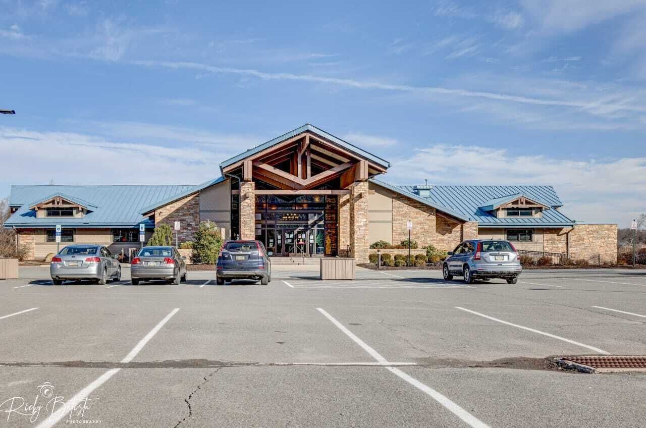 A building with a prominent entrance, parking lot, and a clear sky.