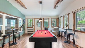 Une table de billard dans une pièce au plancher en bois, un jeu de fléchettes et un panneau indiquant la distance qui sépare l’endroit du stade Lambeau Field.
