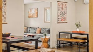 Un salon moderne comprenant un canapé, une table basse et un coin repas avec une table et des bancs.