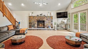 Ein Wohnzimmer mit Kamin aus Stein, einer Couch, einem Couchtisch und einem Fernseher.