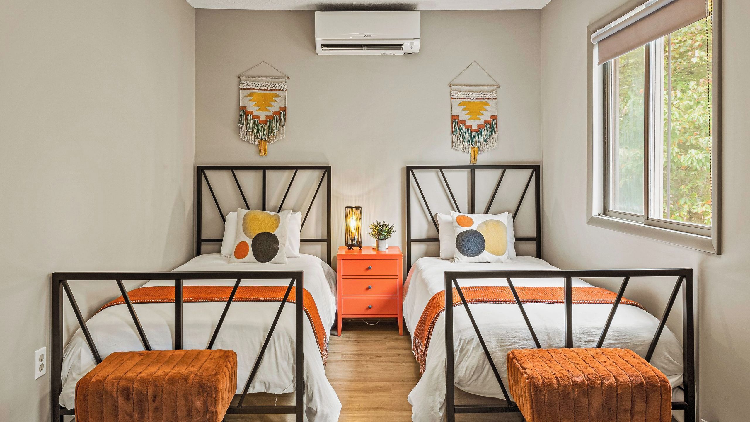 A double room with two beds, a nightstand, an air conditioner, and a window.