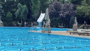 A swimming pool with lane dividers, a slide, and lounge chairs.