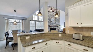 A kitchen with granite countertops, white cabinetry, and pendant lighting. - The Nest at Pinecrest by Avantstay Spacious Deck, Game Room, Fire Pit (Pocono Pines)