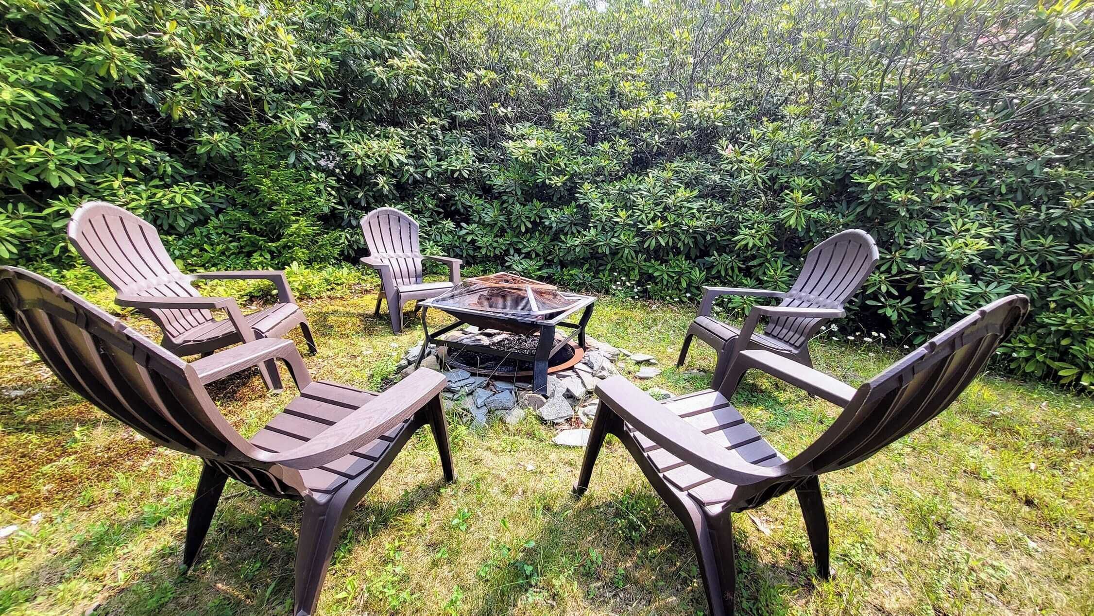 A patio area with Adirondack chairs arranged around a fire pit.