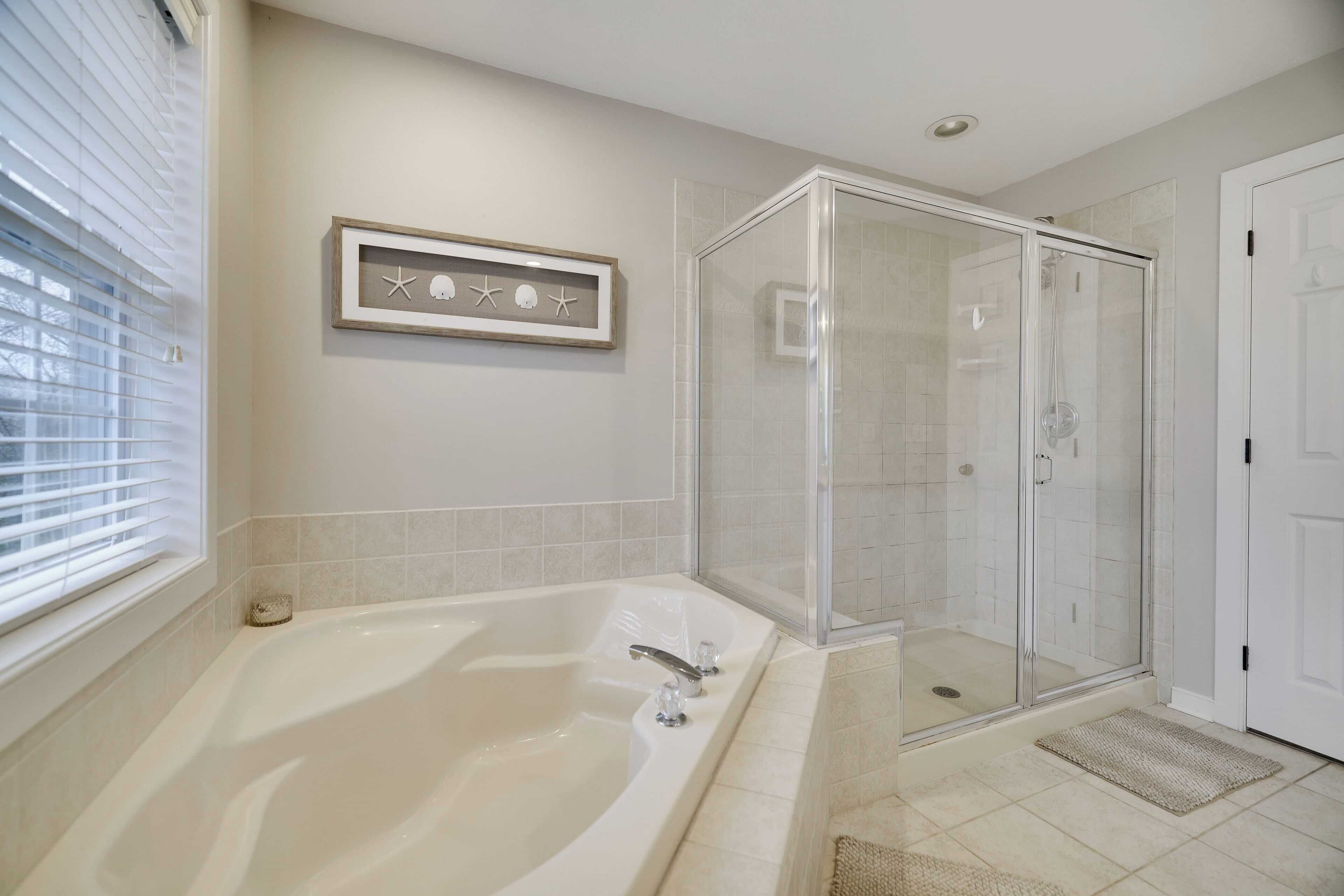 Une salle de bain avec une baignoire, une douche à parois de verre et un tableau encadré au mur.