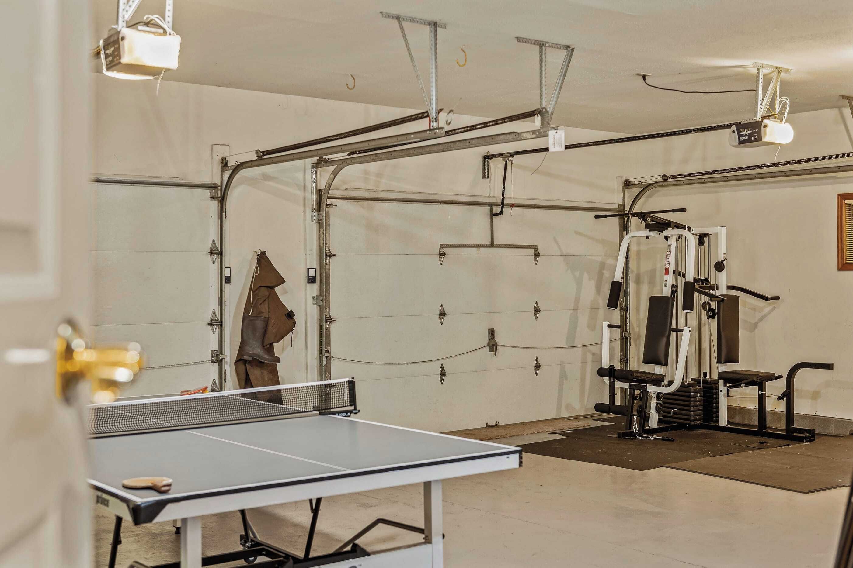 Une salle de sport équipée d’une table de ping-pong, de matériel d’exercice et d’un mur blanc avec une fenêtre.