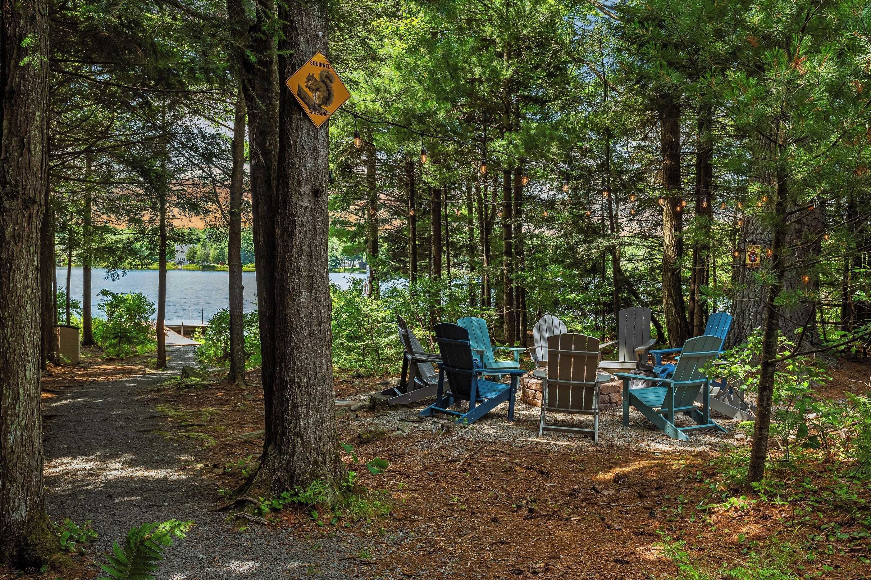 Camping en un bosque con sillas Adirondack y un letrero amarillo que advierte sobre ardillas.