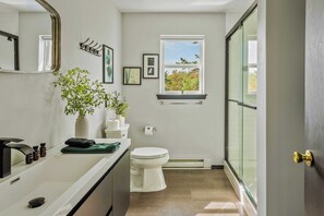 A modern bathroom with a toilet, sink, and a window with a view of trees. - Mountain Mindset by Avantstay Pool, Hot Tub, Game Room, Firepit (Long Pond)