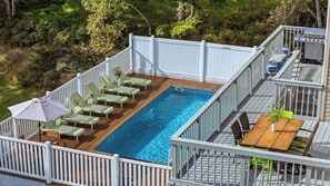 A swimming pool with lounge chairs and a barbecue grill on a deck. - Mountain Mindset by Avantstay Pool, Hot Tub, Game Room, Firepit (Long Pond)