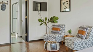 A modern living room with a sofa, a coffee table, a television mounted on the wall, and a large plant. - Mountain Mindset by Avantstay Pool, Hot Tub, Game Room, Firepit (Long Pond)