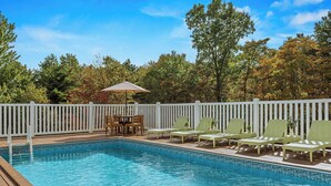 A swimming pool with a wooden deck, white picket fence, and green lounge chairs. - Mountain Mindset by Avantstay Pool, Hot Tub, Game Room, Firepit (Long Pond)