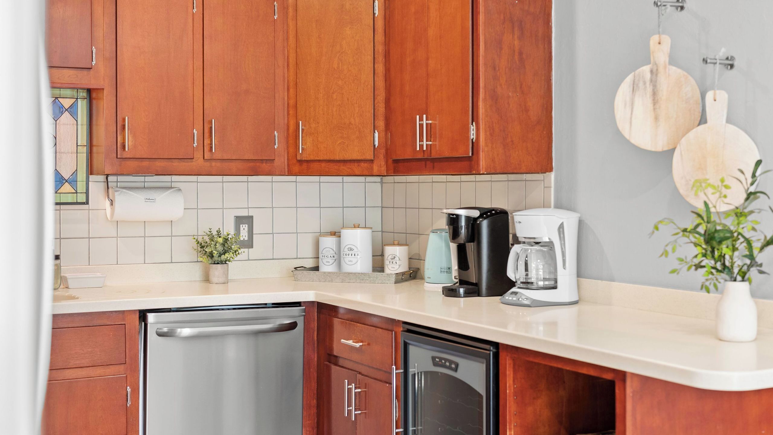 A kitchen with wooden cabinets, a countertop, a coffee maker, a dishwasher, and a potted plant.