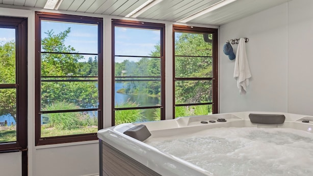 Un baño con una bañera grande, tres ventanas y vistas a un lago.