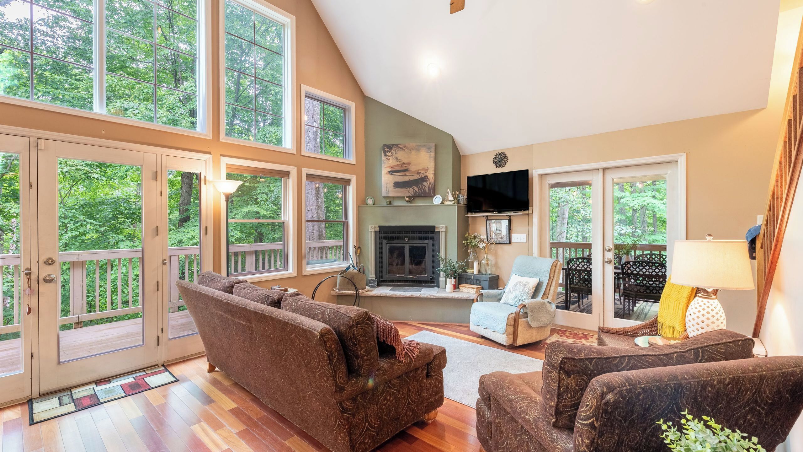 A spacious living room with a fireplace, large windows, and a deck.