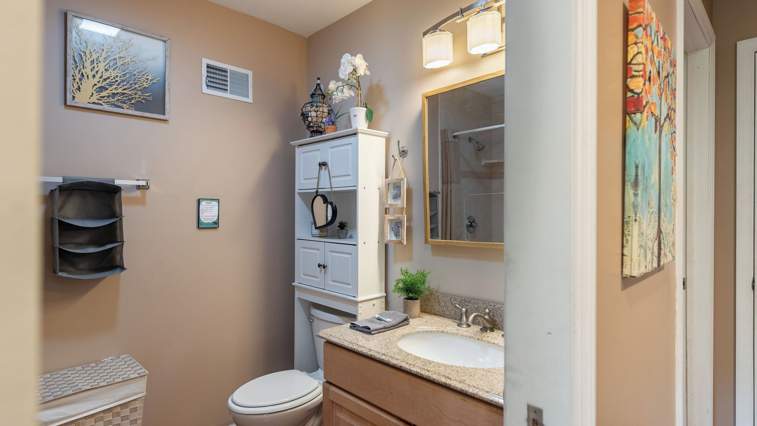 Een badkamer met toilet, wastafel, opbergmeubel en spiegel.