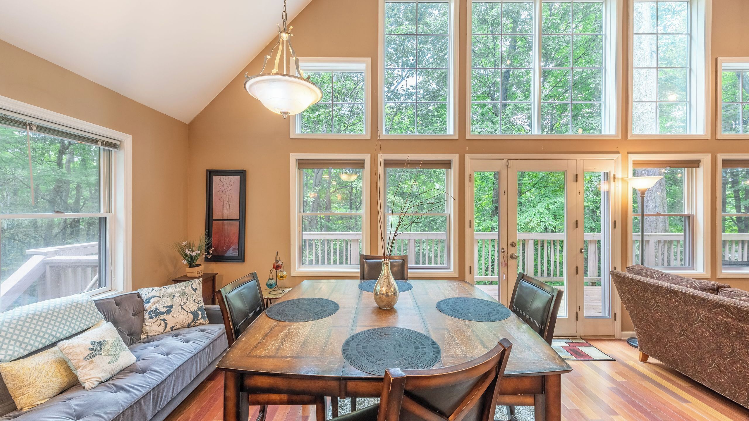 A dining area with a wooden table, chairs, a vase, and a sofa.