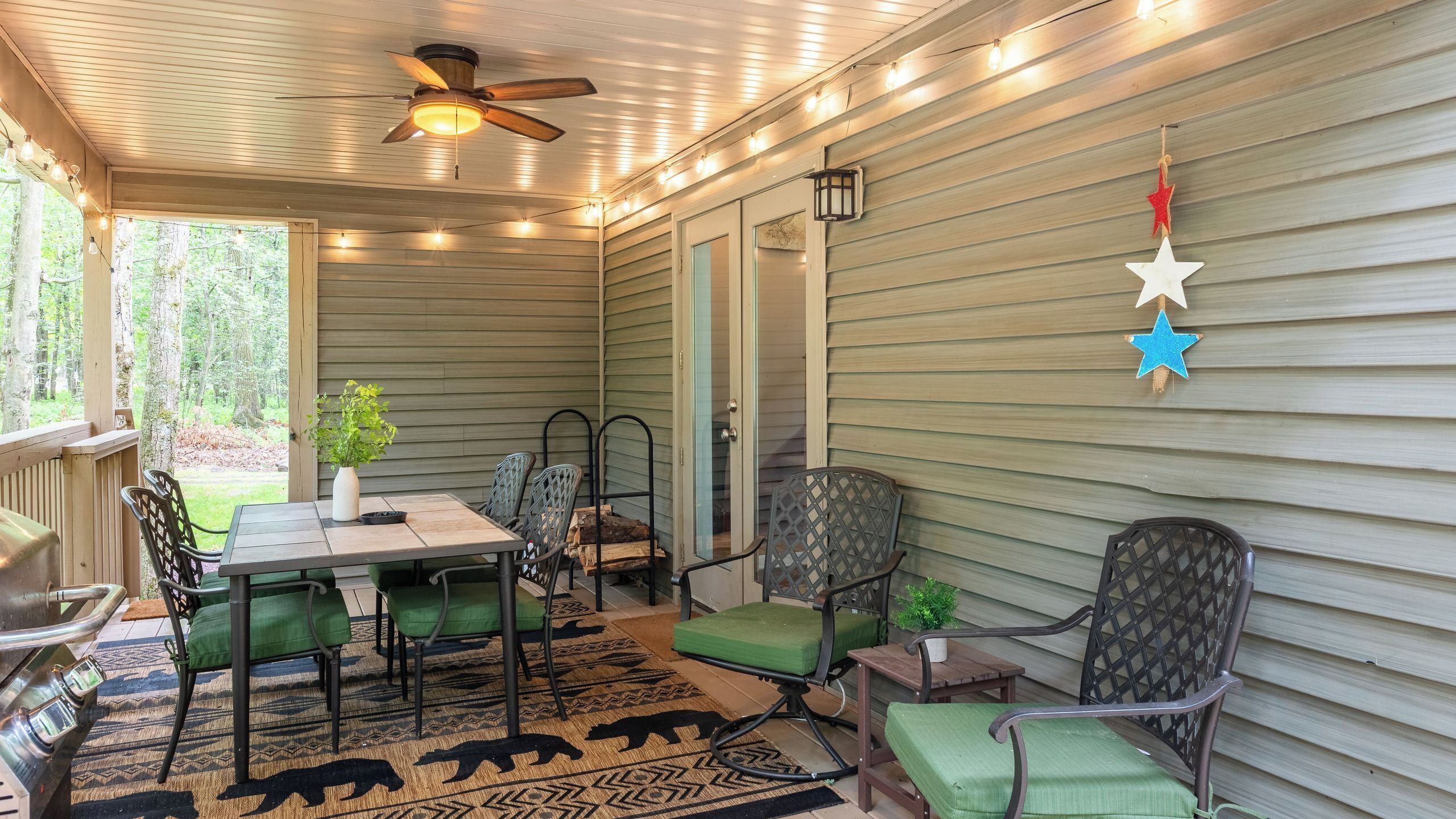 A covered patio with a table, chairs, and a ceiling fan.