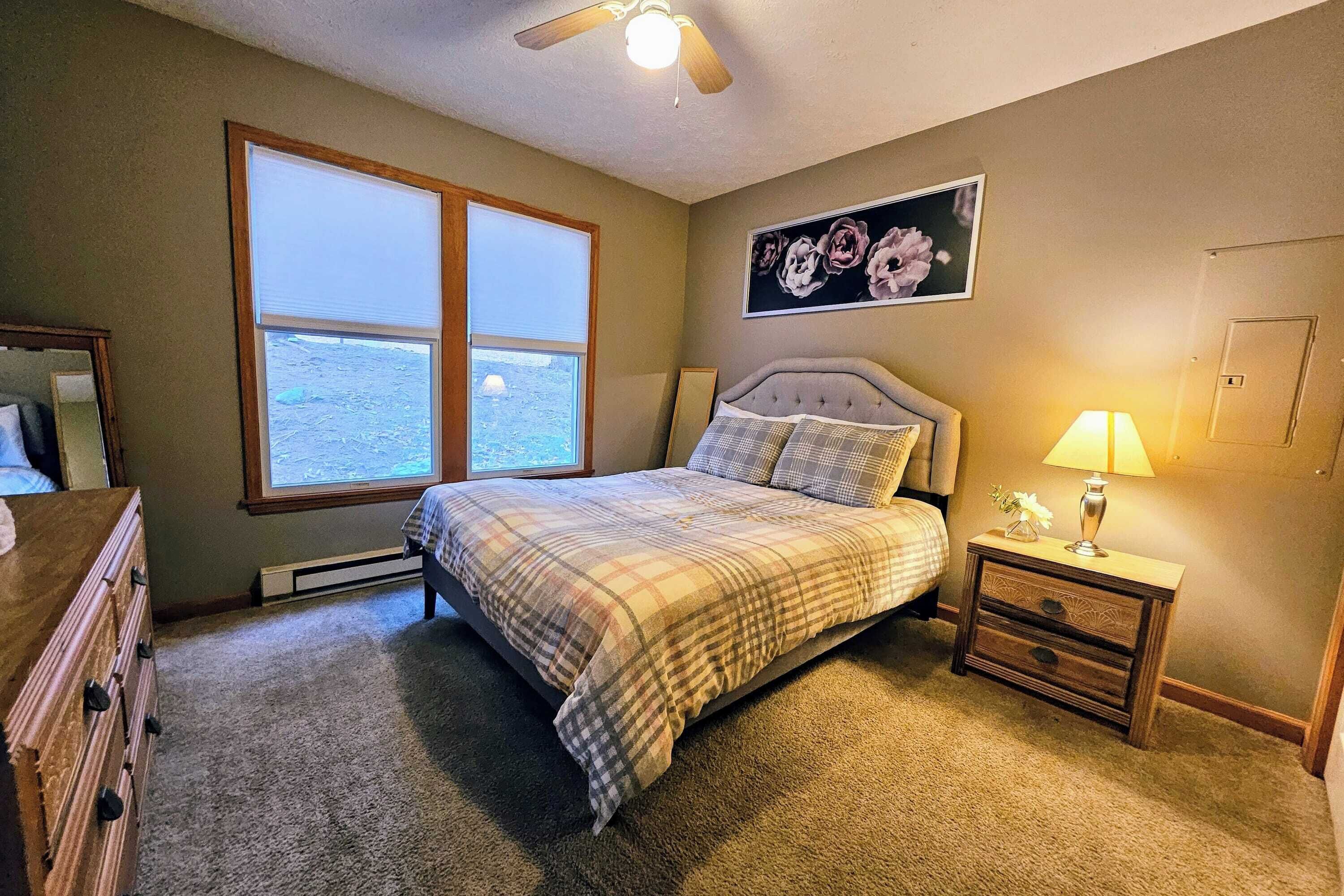 A bedroom with a bed, a nightstand, a window, and a ceiling fan.