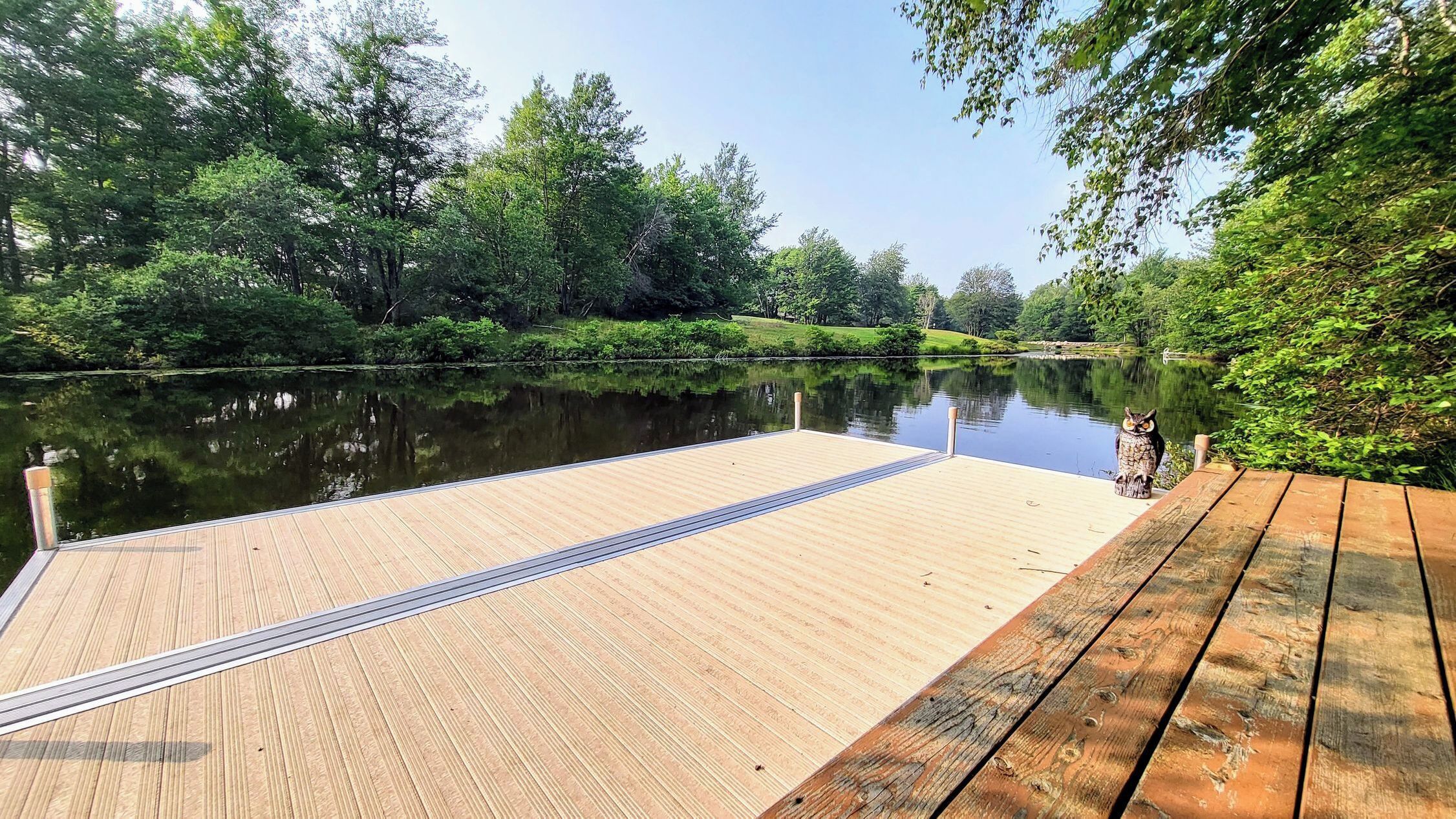 Une jetée en bois s’étendant dans un fleuve paisible, entourée d’une végétation luxuriante et d’arbres.