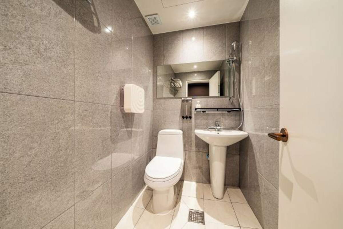 Un baño moderno con inodoro, lavamanos y espejo.