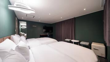 A hotel room with two large beds, a small table, a chair, a TV, and a minibar.