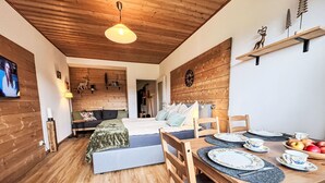 A cozy room with a bed, a dining table set for two, and a wooden ceiling. - Apartment Wolf by Interhome (Feldkirchen in Kärnten)
