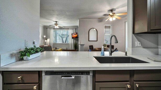 A modern kitchen with a white countertop, stainless steel dishwasher, and dark cabinets. - Shop & Golf! Gem w/ Pool Access in Scottsdale (Scottsdale)