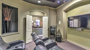 A room with leather reclining chairs, a television, and a door leading to another room. - Shop & Golf! Gem w/ Pool Access in Scottsdale (Scottsdale)