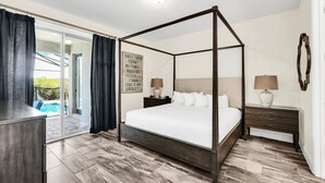 Una cama con dosel, un colchón blanco, una mesita de noche con lámpara y un letrero enmarcado en la pared.